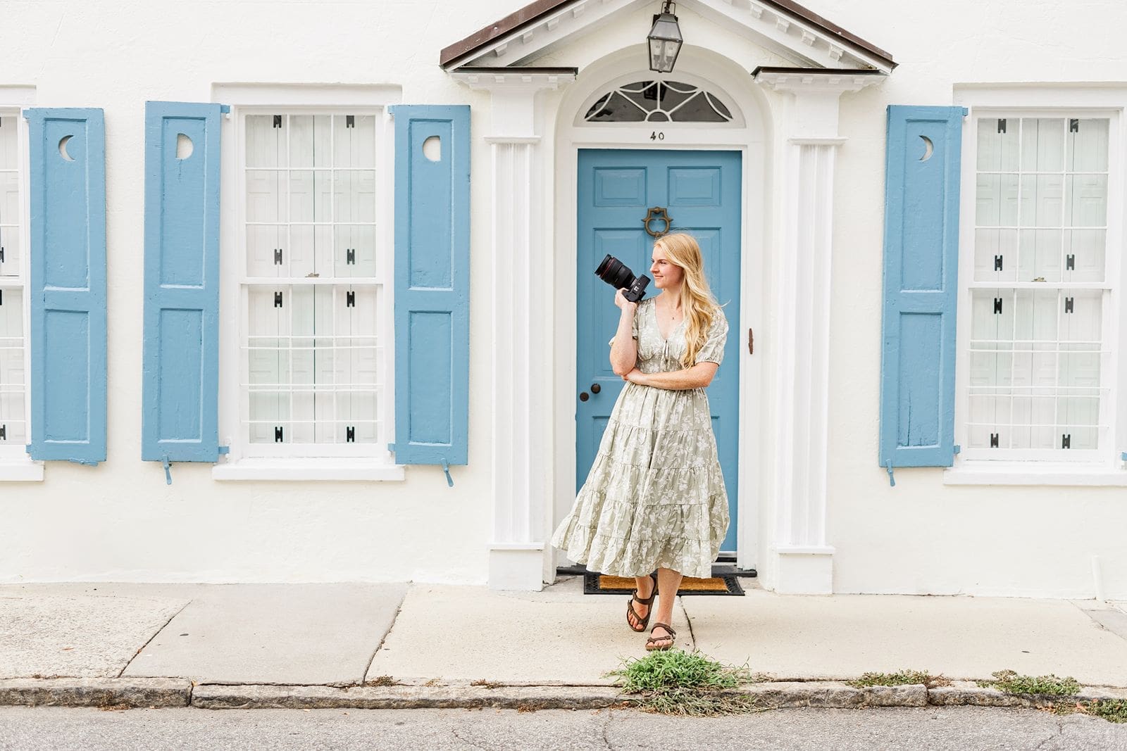 Albuquerque wedding photographer Lelia Graham holding her camera in front of a building with a blue door