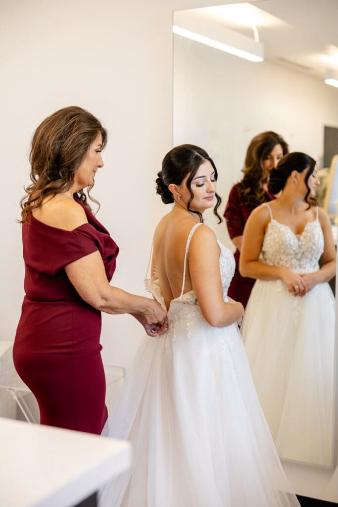 Mother of the bride zipping up the brides dress