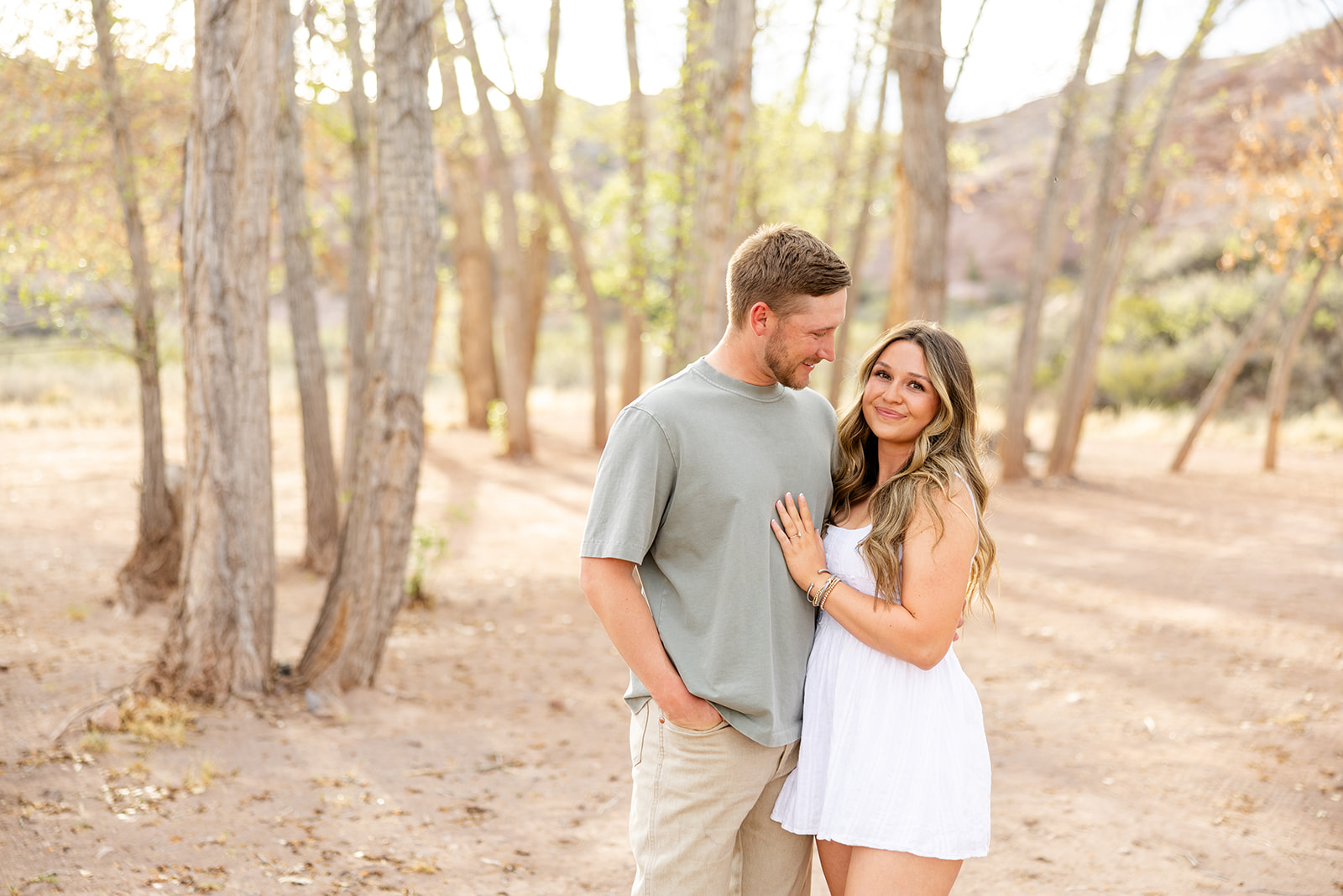 Couple posing for portraits near trees with coordinated outfits